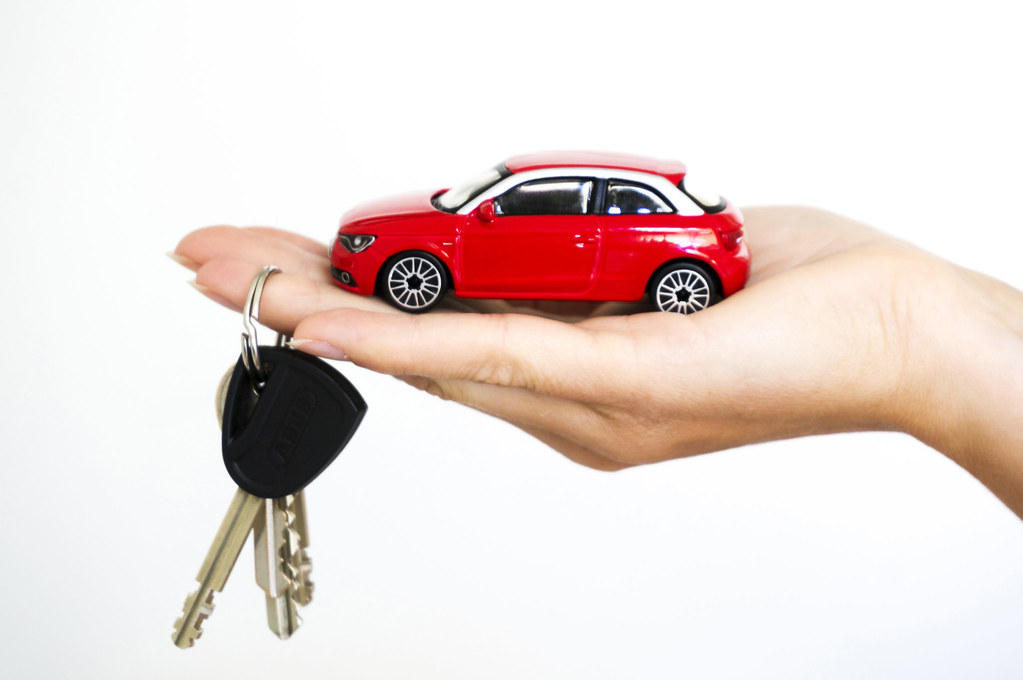 Hand holding a red toy car and car keys