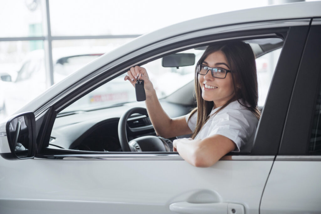 Woman behind wheel of car holding up car keys