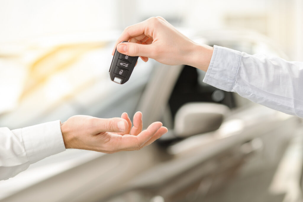 The Hands of One Person Handing Another Person a Car Fob